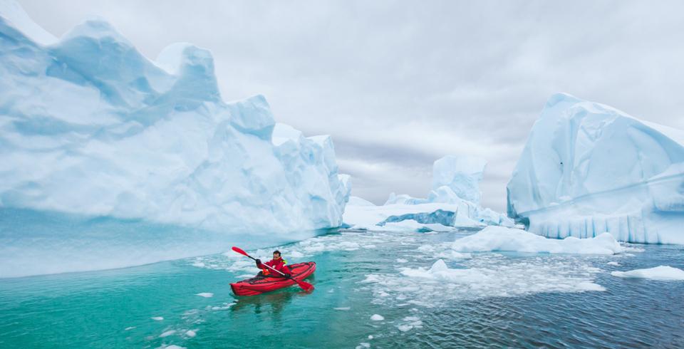 Person kayakying amongst icebergs