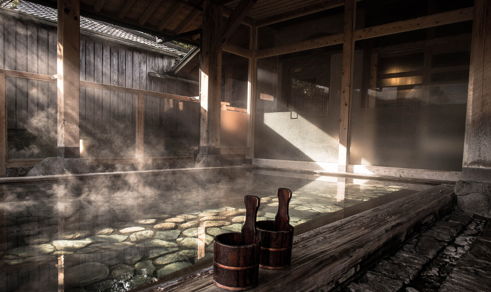 Large indoor onsen in a wooden room and steaming water