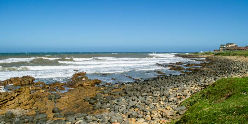 A rocky shore with huts in the background