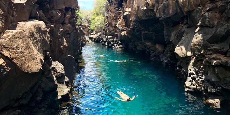 A woman swimming between two cliffs