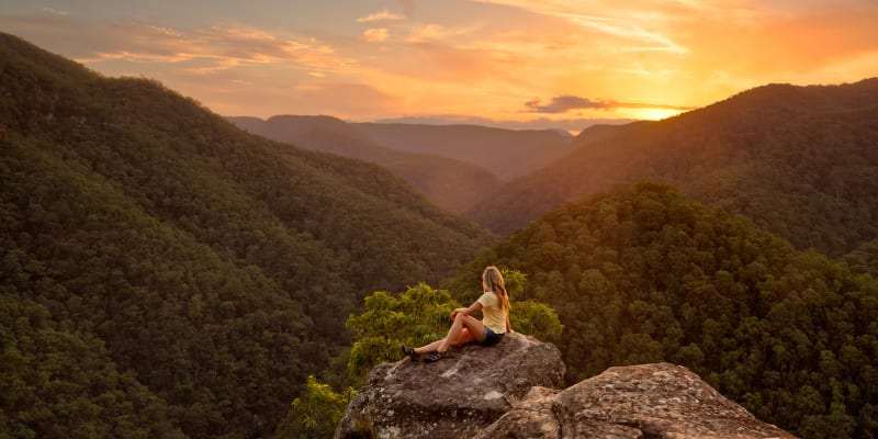 Woman sat on a rock in the Blue Mountains at sunset