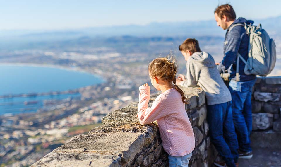 A father and two children at a view point looking over a bay
