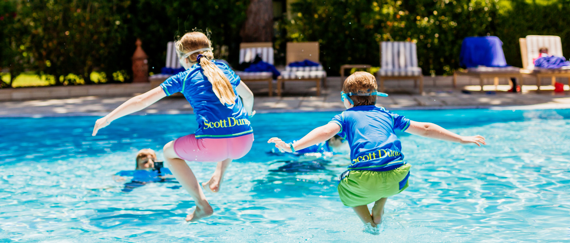 Two children jumping into a swimming pool
