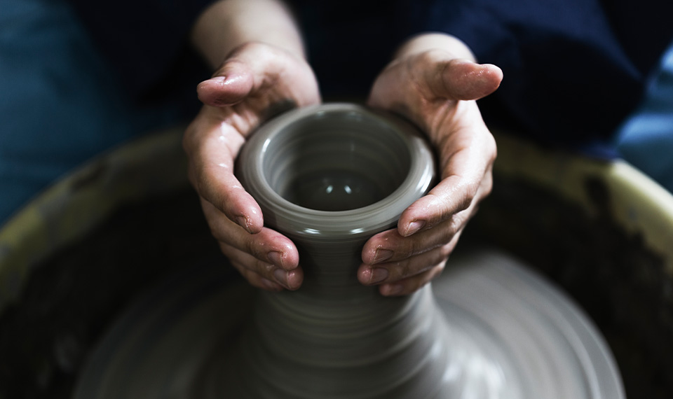 Someone forming a vase on the pottery wheel