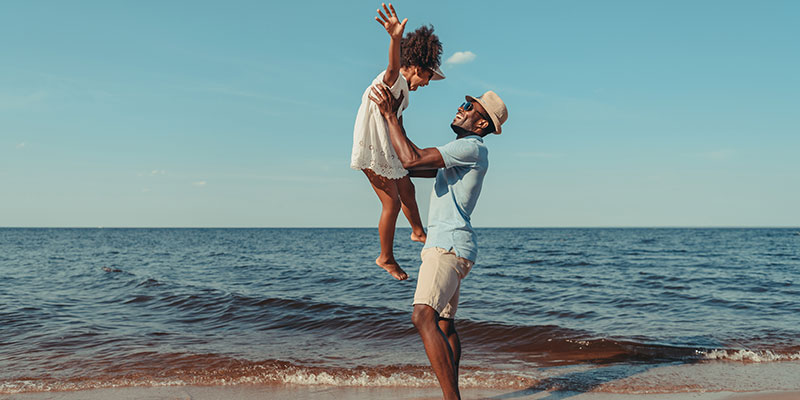 A father playing with his child at the beach 