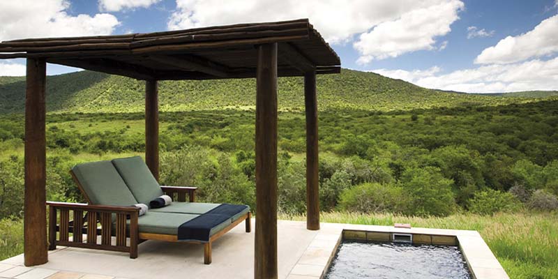 An outdoor sitting area and hot tub with grasslands in the background