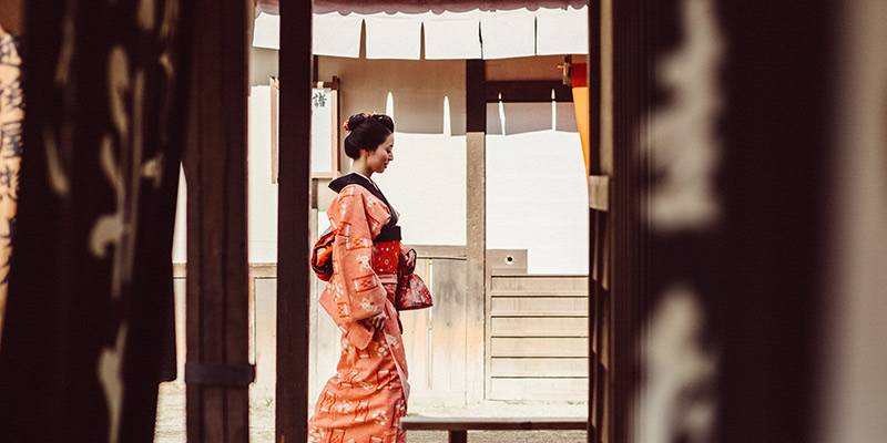 A geisha walking down a back street