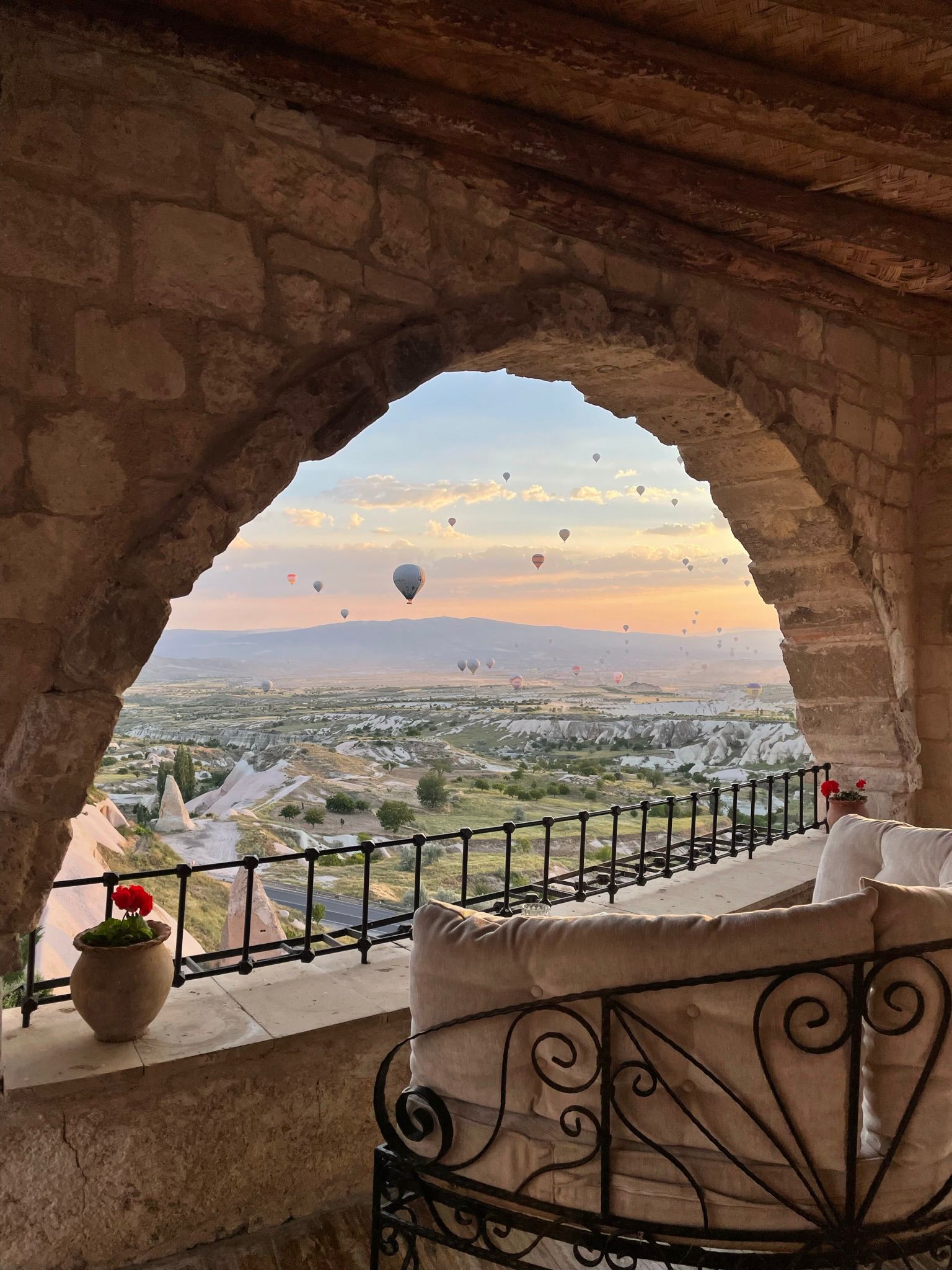 view through a stone arch of hot air balloons in the sky