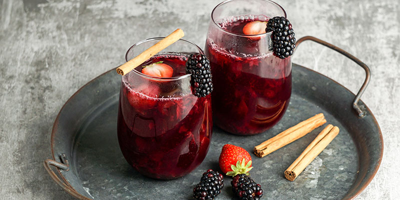 Two glasses of colada morada with cinnamon sticks