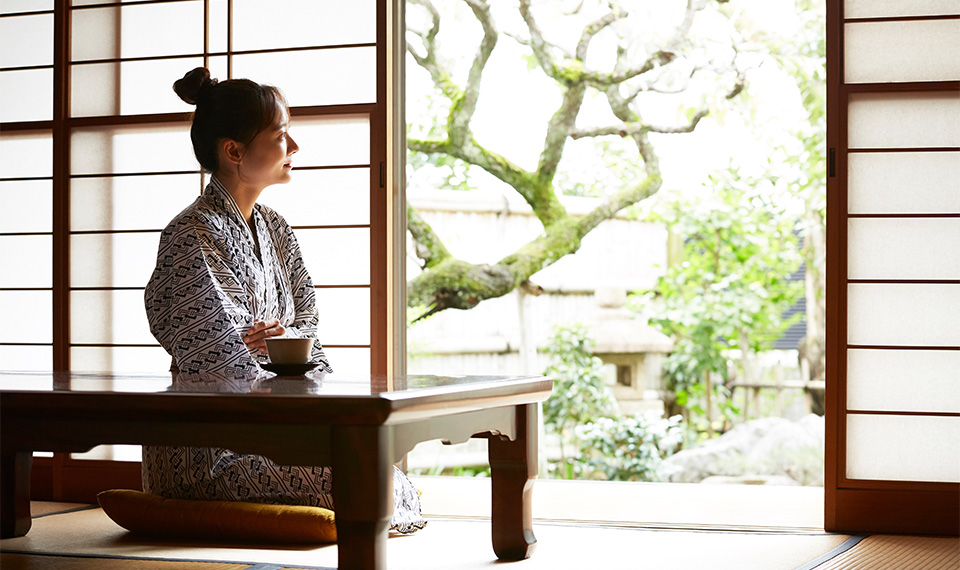 A women sitting in a ryokan room in her yukata staring out at the garden