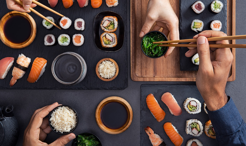 Sushi boards on a table being picked up by chopsticks