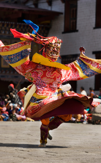 Colourfully dressed dancer in sacred Tshechu celebration in Bhutan