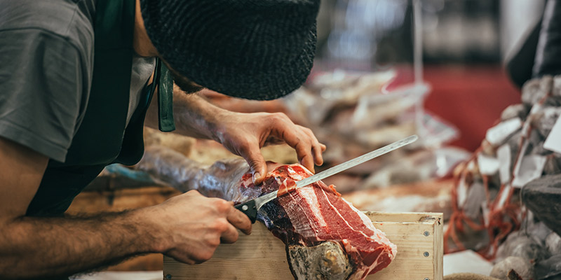 A butcher skilfully slicing prosciutto