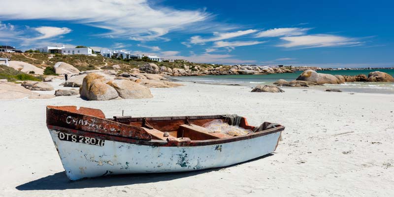 An old boat sitting on white sand by the beach