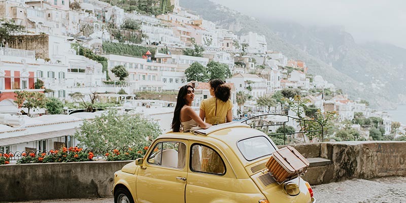 Two women standing out of a sunroof