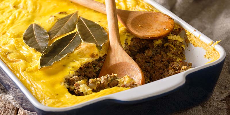 Bobotie dish with two wooden spoons