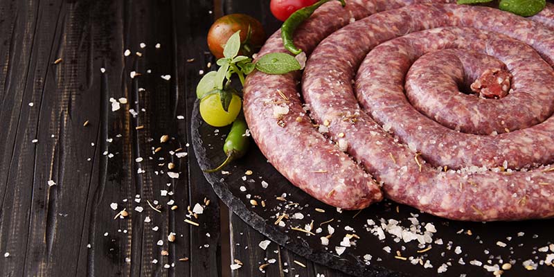 A plate of raw boerewors dressed in salt and grape tomatoes