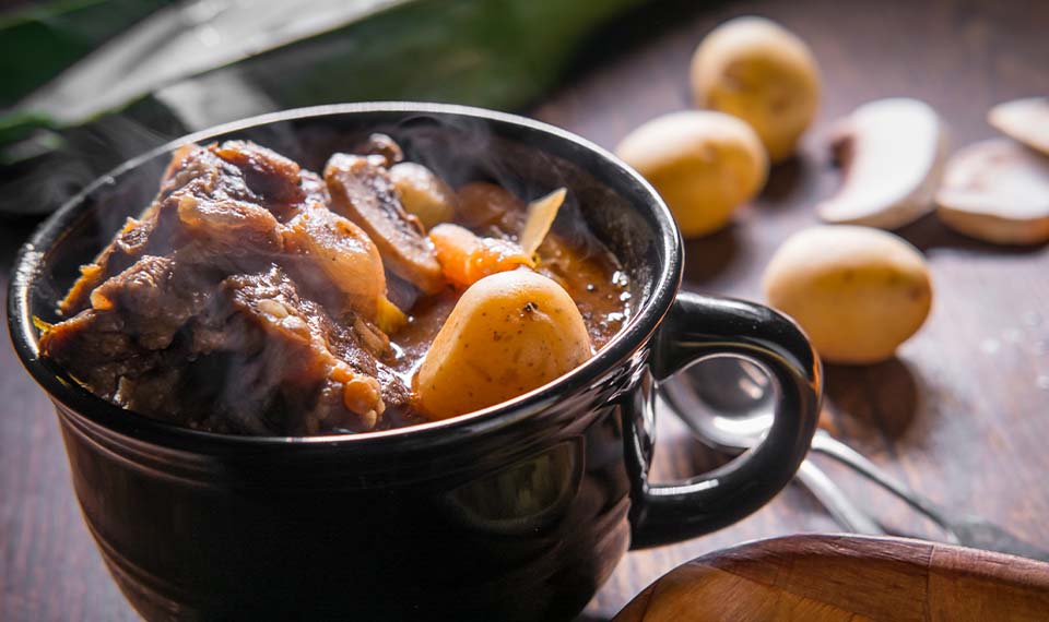Potjiekos served in a mug on a wooden table