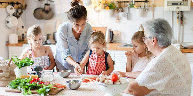 A mother, grandmother and daughters all making pizza