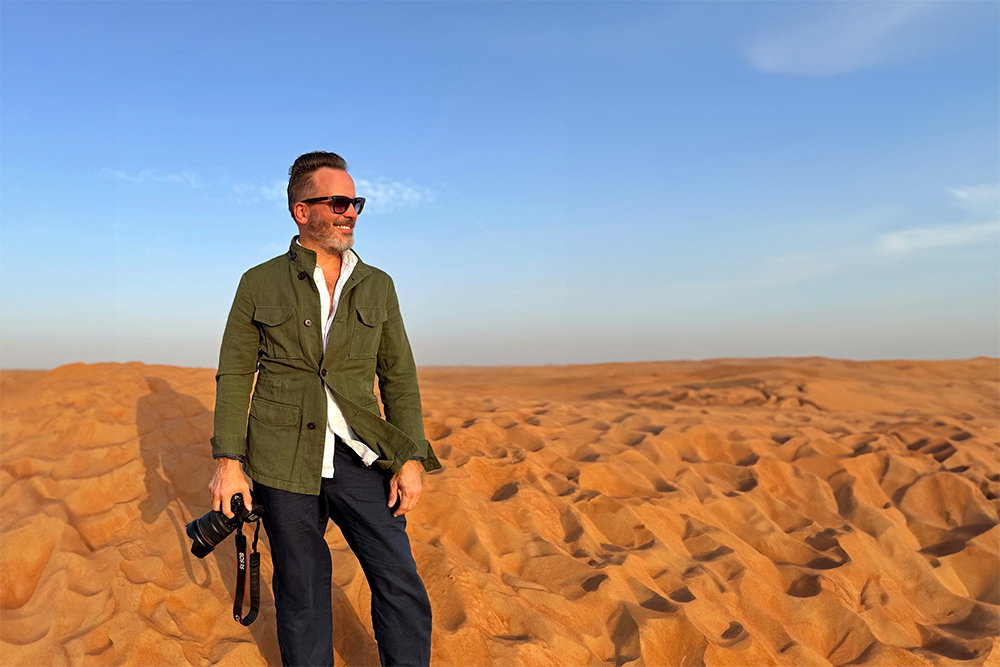 Scott Woodward stood smiling in the desert holding a camera