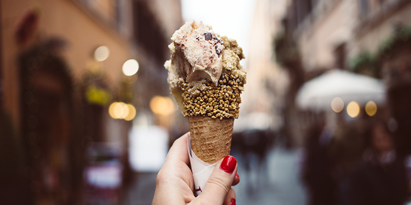 A hand holding up a cone of gelato