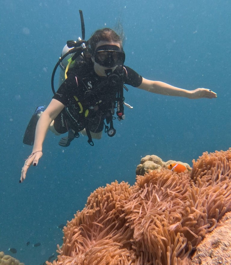 Scott Dunn travel consultant diving near a clown fish in the Maldives