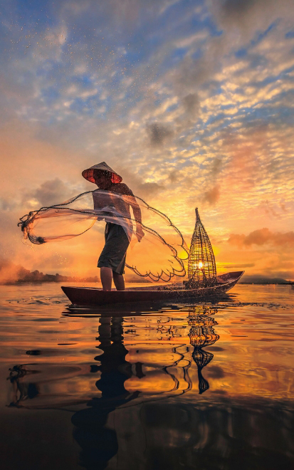A man on the Mekong River with the sunset in the background